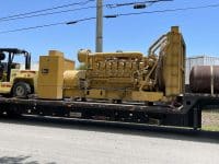 Massive Industrial Generator Being Loaded Onto A Flatbed Trailer For Transporting.